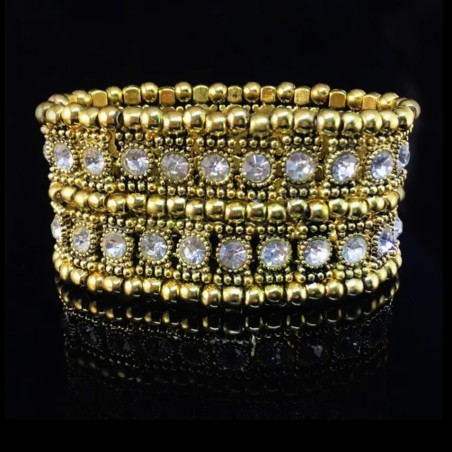 Bracelet élastique serti de pierres cristal, perles et matériaux dorés.